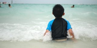 暑假里，一个亚洲小男孩坐在沙滩上
