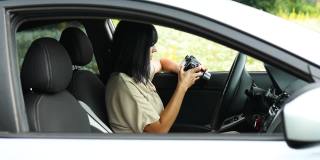 一个女摄影师坐在车里看着相机上的照片