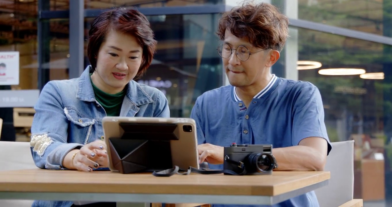 亚洲夫妇和家庭在咖啡厅或地方使用免费wifi 5G上网笔记本电脑，用信用卡进行网上购物。活动周末假期一起旅行快乐。