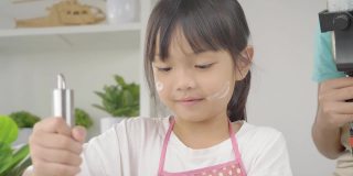 亚洲女孩拍摄视频，她的姐姐在家自制饼干，为病毒视频或TikTok在家，新一代的时尚生活理念。