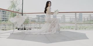 一位年轻漂亮的亚洲女子，身着婚纱，手持一束鲜花，坐在婚礼现场的遮阳伞下