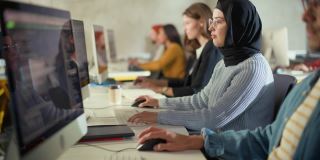 多元族群的男女学生坐在大学教室，学习计算机科学。青年学者在大学学习计算机信息技术，在课堂上编写代码。