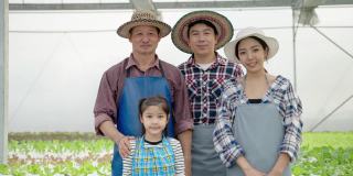 一个亚洲有机蔬菜农民家庭的肖像站在那里，微笑着对产品和服务的质量充满信心。