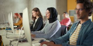 多元族群的男女学生坐在大学教室，学习计算机科学。青年学者在大学学习计算机信息技术，在课堂上编写代码。