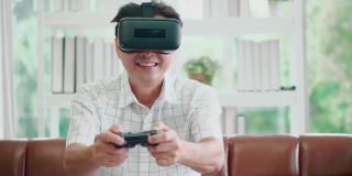 亚洲老年男子手持操纵杆，戴着虚拟现实眼镜在客厅玩VR游戏，科技生活方式人们在度假