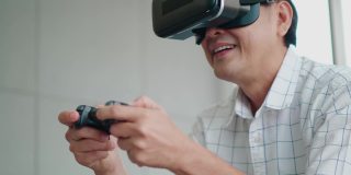 亚洲老年男子手持操纵杆，戴着虚拟现实眼镜在客厅玩VR游戏，科技生活方式人们在度假