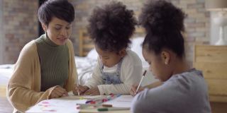 亚洲母亲帮助她的两个非洲女儿和教绘画作业在公寓