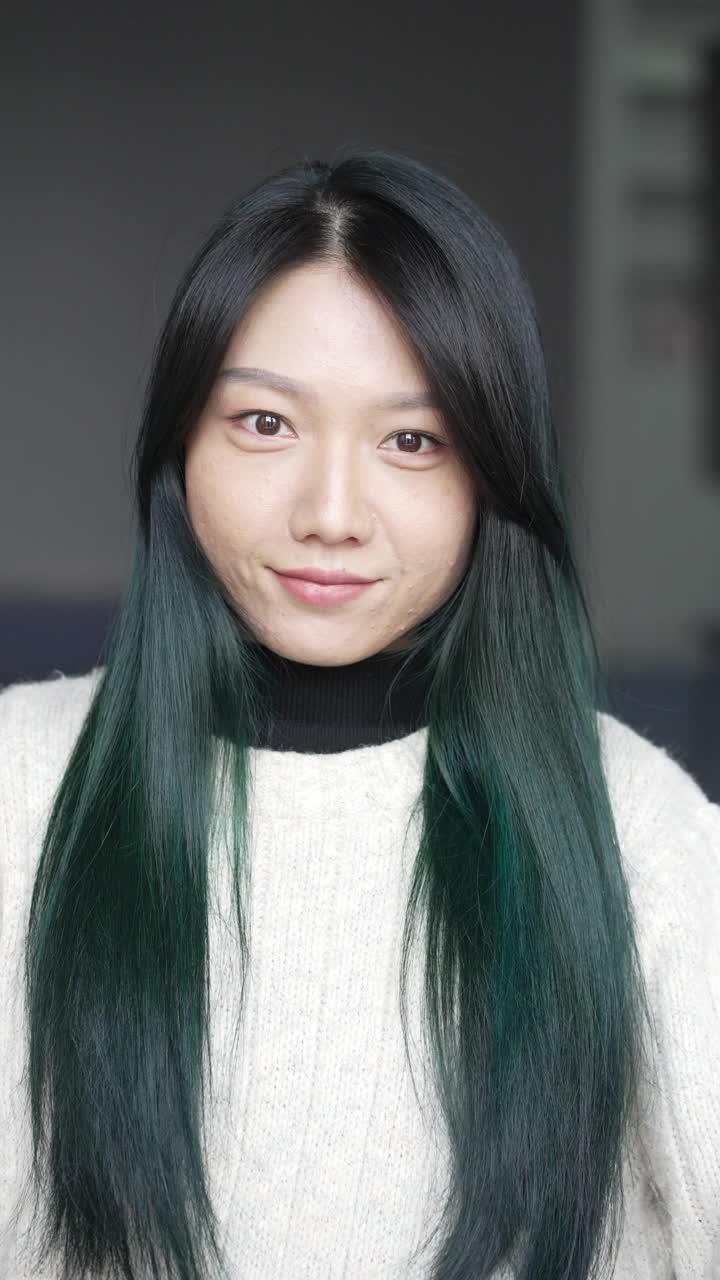 一个绿色头发的年轻亚洲女人在镜子里梳头发