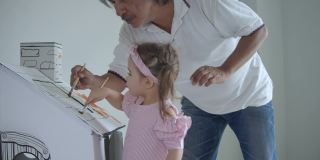 父亲和女儿在家里客厅的玩具屋里画水彩画