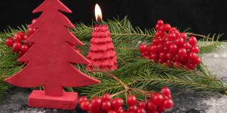 圣诞节的静物与红色的荚莲浆果，圣诞树，燃烧的蜡烛和雪在黑色的背景