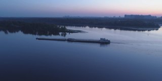 鸟瞰图。日出时在河上推驳船的拖船。