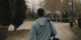 强壮的男人和运动员在去健身房的路上，背着运动背包穿过一个公园