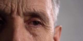 满脸皱纹的男人脸上流着眼泪。这位老人的半张脸特写。