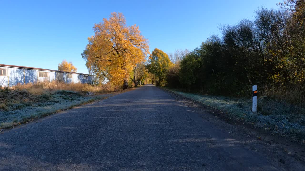 从汽车上看秋天的风景，秋天的乡村风景中的彩色树木和晴天的蓝天。
