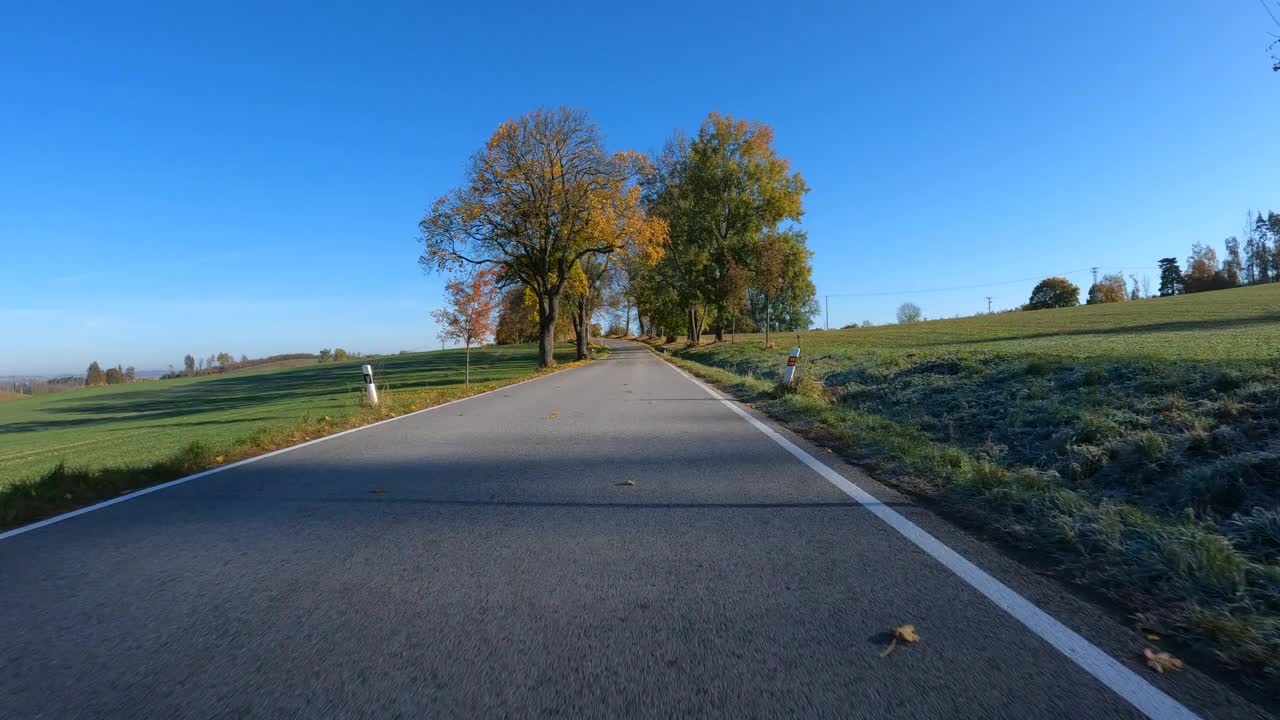 从汽车上看秋天的风景，秋天的乡村风景中的彩色树木和晴天的蓝天。