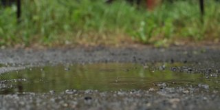 一个穿着黄色胶靴的孩子在雨中的水坑里奔跑玩耍