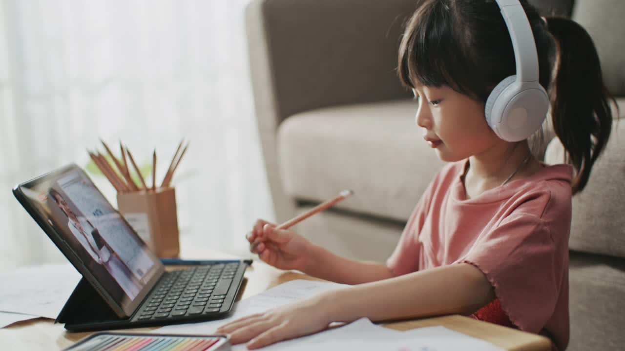 亚洲女儿在家里用数字平板电脑做在线作业，在线学习