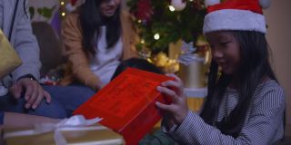 快乐的一家人带着女儿戴着圣诞帽，在圣诞节的时候聚在一起，享受打开礼品盒的乐趣