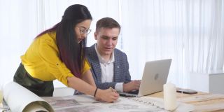 亚洲女性女性设计师与白人男性建筑师合作项目，为建筑房地产创造新的建筑设计。创意团队设计师在现代办公室工作蓝图。