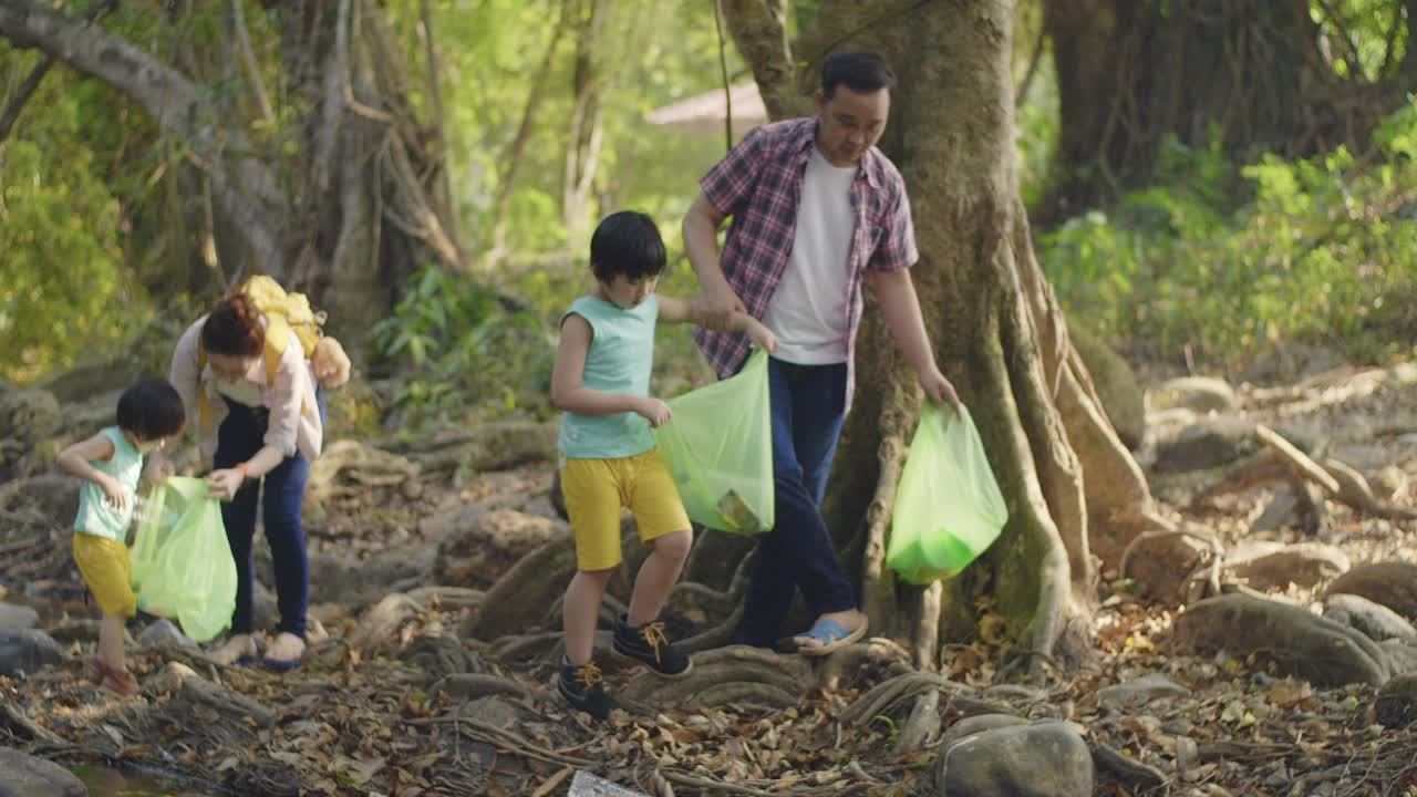 亚洲家庭志愿者在河上捡起一个塑料瓶