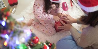 小女孩在妈妈的帮助下为圣诞节打包礼物