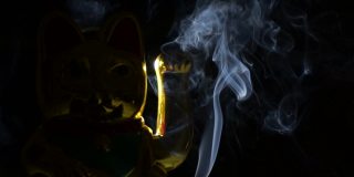 Maneki neko中国幸运猫，烟和黑色背景