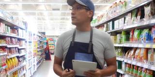 一位亚洲杂货店经理使用电子平板电脑工作