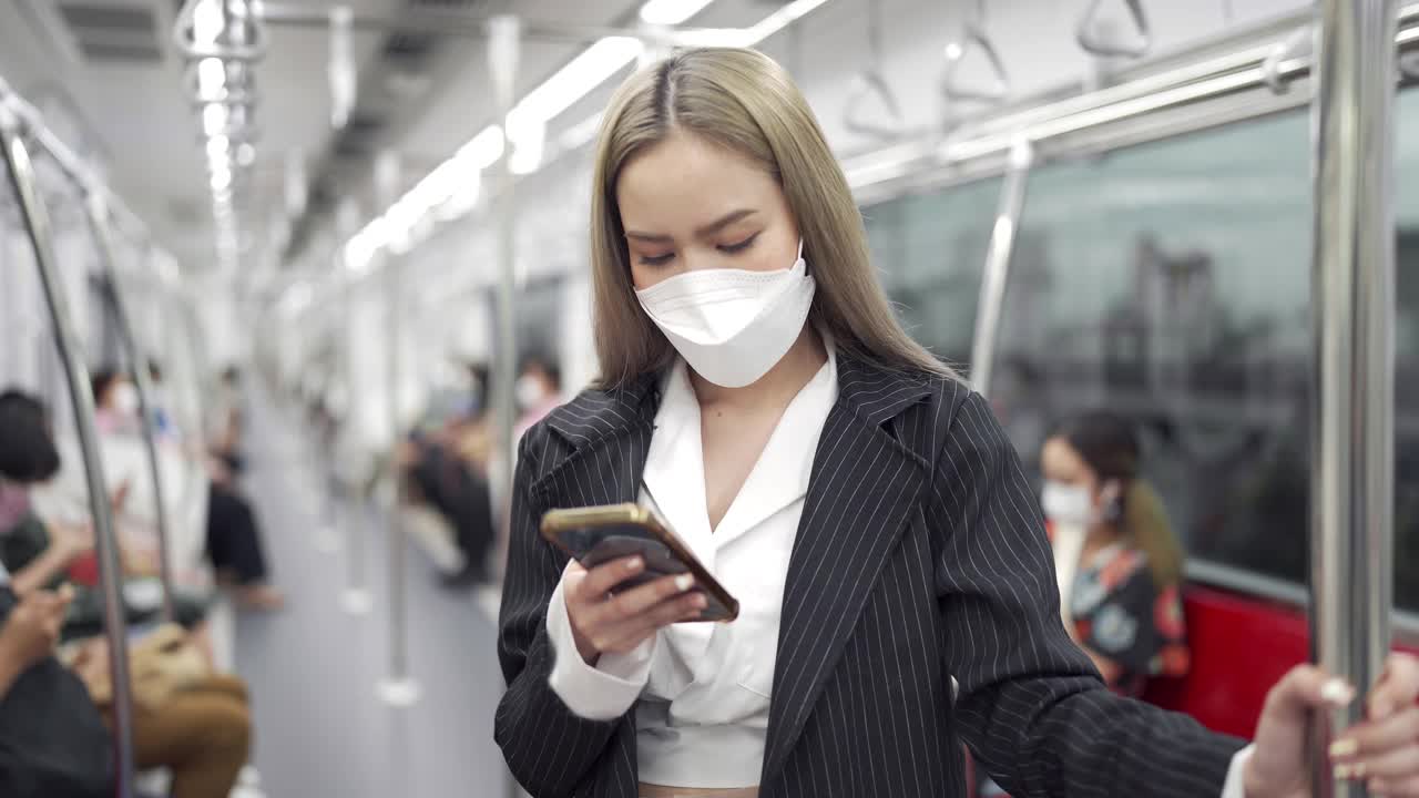 坐地铁时戴着口罩用智能手机的4K女商人