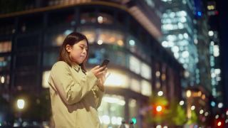 年轻的女商人晚上在城市里使用智能手机视频素材模板下载