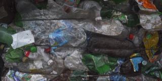 在废物回收厂为垃圾回收准备的一捆压过的塑料瓶。镜头从下到上移动。污染问题。稳定的视频