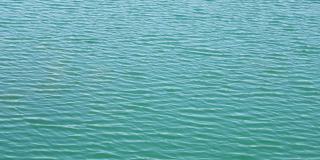 无缝无人机在碧绿的湖水涟漪接近视图。鸟瞰图的海或海洋与美丽的波浪图案的景观，无尽的海蓝宝石水在夏天的日子