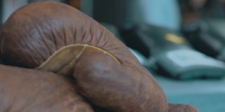在模糊的背景上旧的棕色皮革拳击手套的特写。视频。运动概念和运动器材