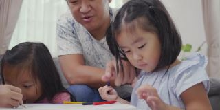 可爱的亚洲小女孩在画上画，在家里用彩笔画画