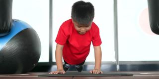 亚洲男孩在健身房做俯卧撑和瑜伽