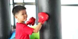 亚洲男孩微笑着在健身房练拳击、骑自行车
