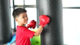 亚洲男孩微笑着在健身房练拳击、骑自行车视频素材模板下载