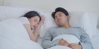 亚洲魅力有趣的男性自拍与睡觉的女友在床上。幸福的家庭，新婚夫妇一起度过早上的时间，丈夫躺在卧室里给妻子拍照。