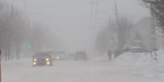 冬天。暴雪暴雪。汽车在城市的雪道上行驶。慢动作降雪。恶劣的天气状况影响了交通。有发生交通事故的危险。十字路口
