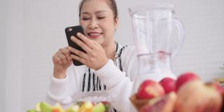 亚洲资深女性网红，一边教如何自制不同口味和酸奶的水果冰沙，一边查看粉丝。健康天然益生菌调味饮品，在厨房学习使用科技，低角度视角。
