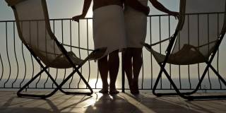 相爱的情侣拥抱在阳台上，欣赏海边的日落