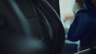 在汽车详细清洁服务期间，一位年轻人在清洁座椅坐垫时使用精细的布对汽车内部进行深层清洁。视频素材模板下载