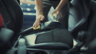 在汽车详细清洁服务期间，一位年轻人在清洁座椅坐垫时使用精细的布对汽车内部进行深层清洁。视频素材模板下载