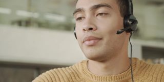 微笑英俊的拉丁裔男子通过头戴耳机的视频连接与客户沟通