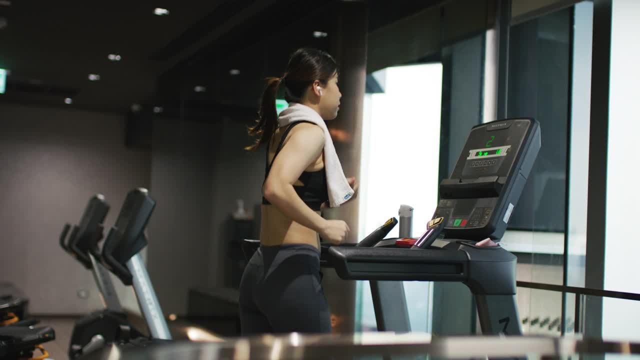 年轻女子在健身房的跑步机上锻炼和慢跑