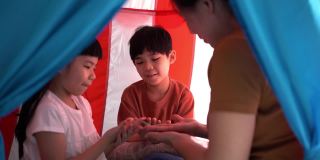 年幼的兄弟姐妹和妈妈在帐篷里玩耍