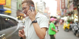 一名4K亚洲男子在泰国曼谷夜市街头使用智能手机旅行