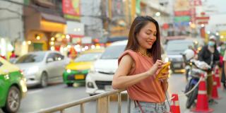 在泰国曼谷的夜市，4K亚洲女性正在使用智能手机旅行