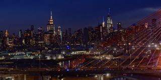 在灯火通明的科修斯科大桥上，曼哈顿中城天际线的夜景。航拍视频与快速平移摄像机运动。