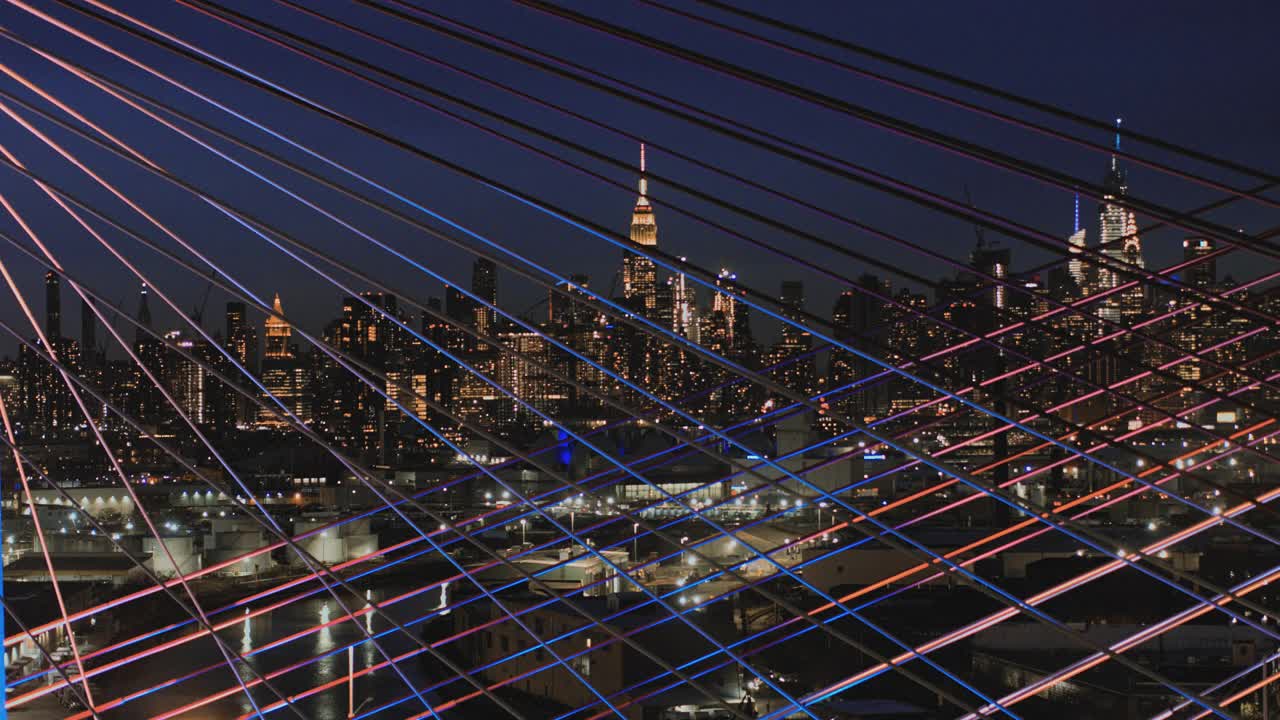 在灯火通明的科修斯科大桥上，曼哈顿中城天际线的夜景。航拍视频与平移摄像机运动。