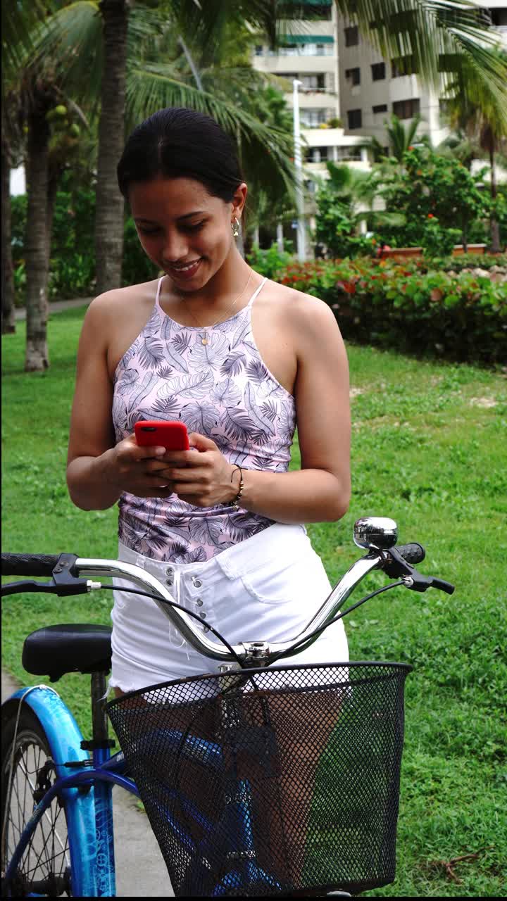 年轻女子在城市里骑自行车时查看手机